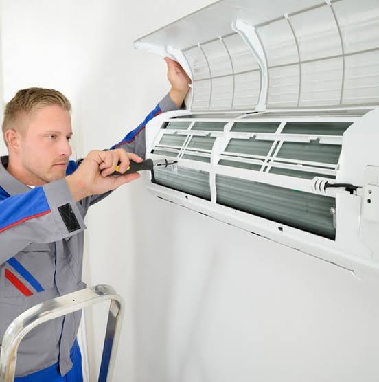 Technician cleaning an indoor air conditioner filter and evaporator coil