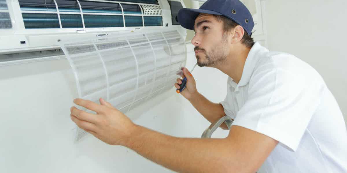 Technician inspecting and servicing an indoor air conditioning unit