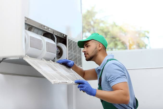 Technician maintaining an indoor HVAC unit and its air filter