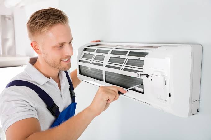 Technician cleaning a wall-mounted indoor air conditioning unit