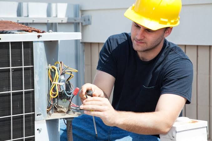 Technician completing an outdoor air conditioning electrical repair