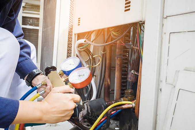 Technician checking refrigerant connections and system pressures