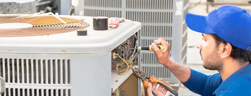Technician servicing an outdoor condenser during an HVAC installation visit